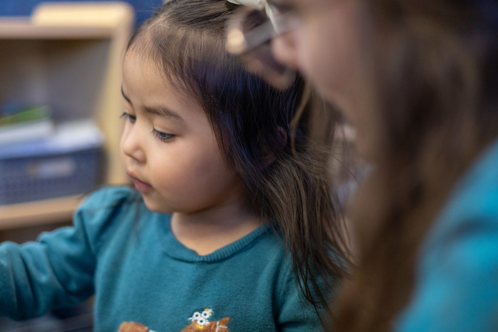 Toddler girl focused on a hands-on activity at ABC Child Development Center East in Greeley CO